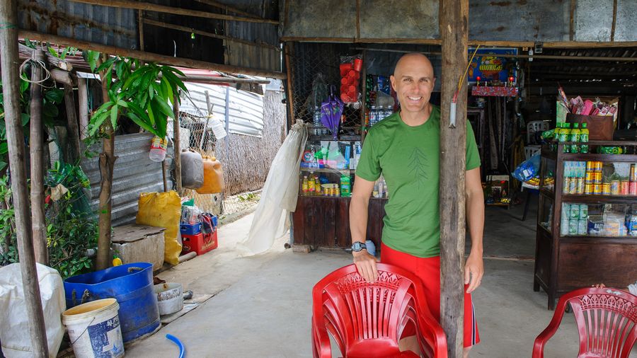 Standing in a roadside shop with stacked red plastic chairs, Hoi An